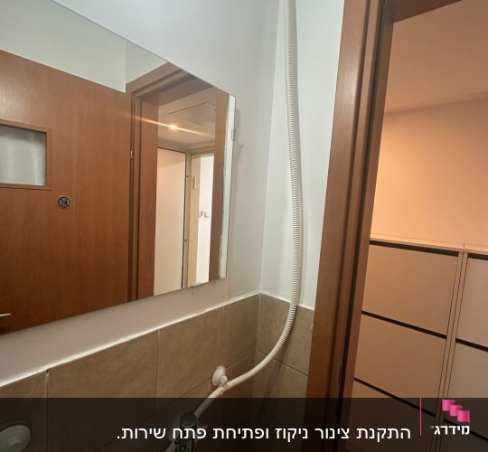 חדר אמבטיה עם כיור וצינור גמיש על הקיר